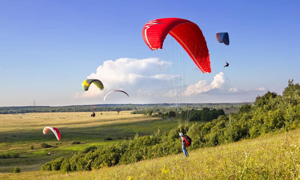 Flere paraglidere seiler over landskapet