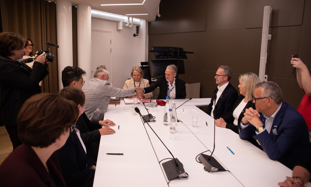 Delegasjonsledere tar hverandre i hendene.
