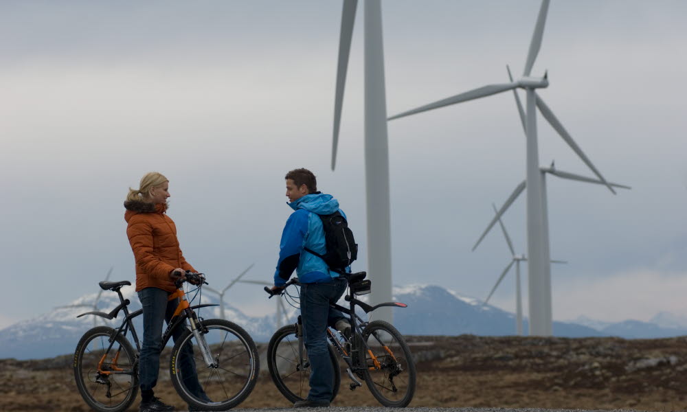 Mann og kvinne på sykkeltur blant vindmøller