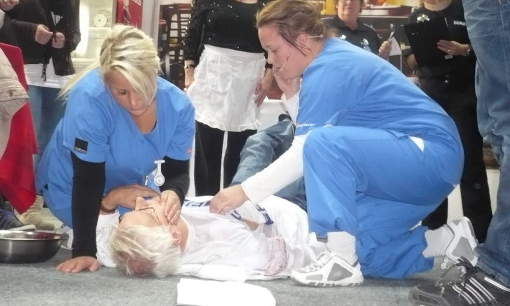 To sykepleiere under utdanning praktiserer førstehjelp på en dokke. 