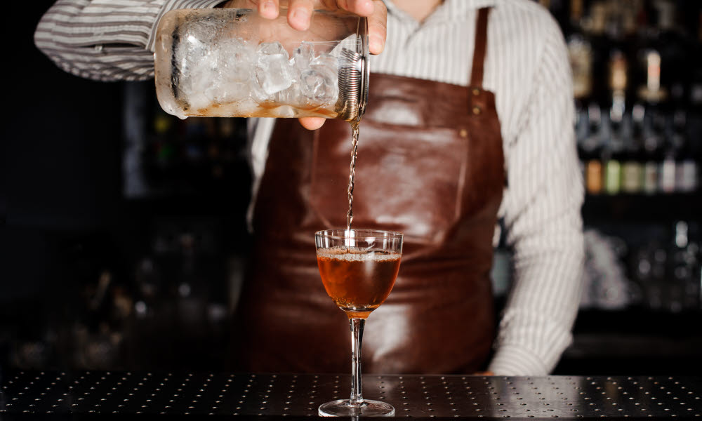 En bartender heller drink i et glass